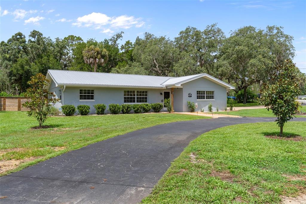 A light gray single-story house with a metal roof sits behind a curved asphalt driveway — 914 N MCGOWAN AVENUE, CRYSTAL RIVER, FL