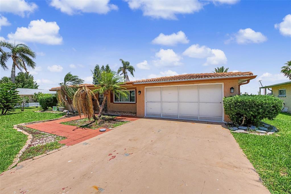 A single-story house with a tan exterior, a tiled roof, and a concrete driveway — 3837 TOPSAIL TRAIL, NEW PORT RICHEY, FL