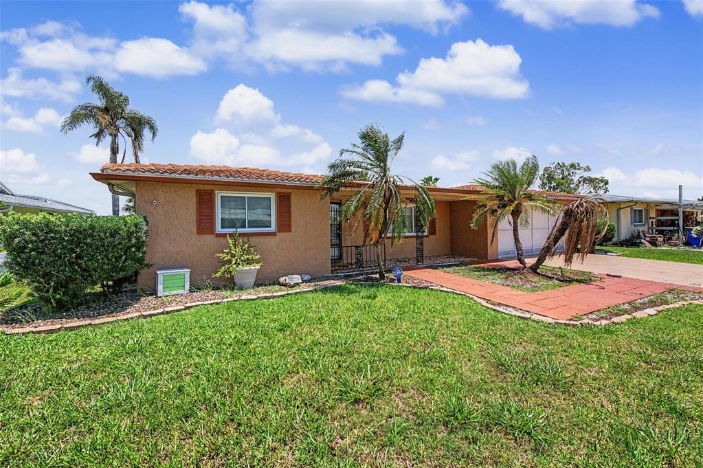 A single-story house with a tan stucco exterior, a tiled roof, and palm trees — 3837 TOPSAIL TRAIL, NEW PORT RICHEY, FL