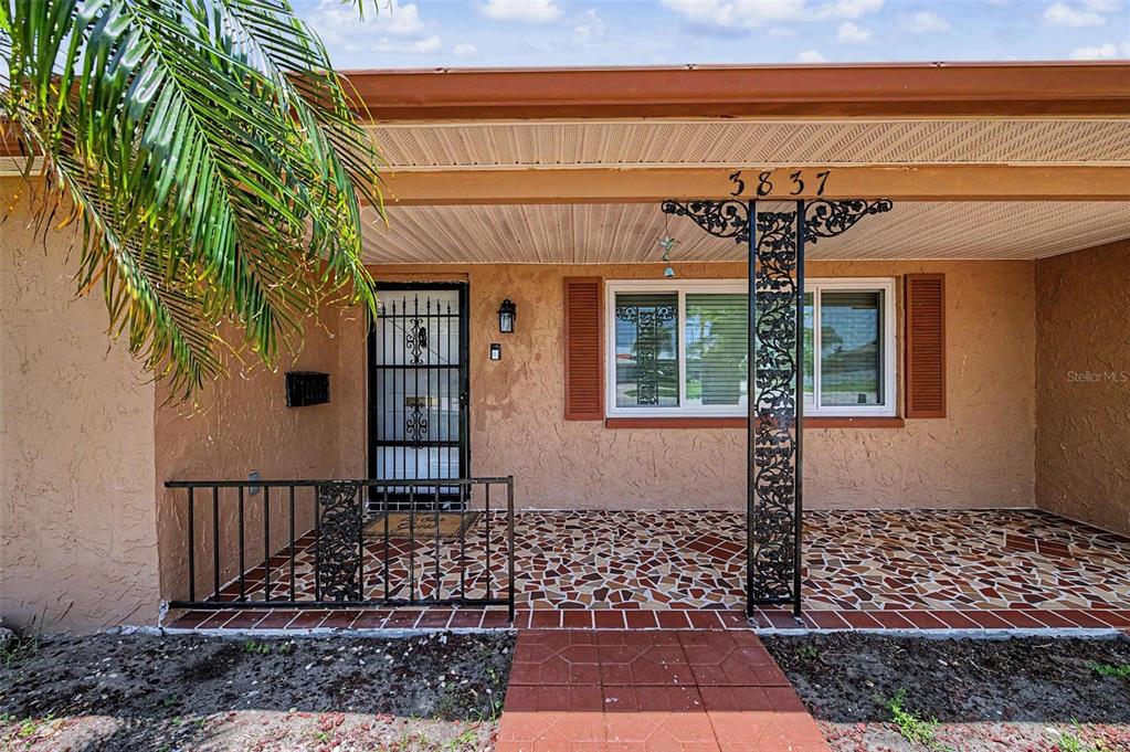A front porch with a tiled floor, a decorative metal support post, and a screen door — 3837 TOPSAIL TRAIL, NEW PORT RICHEY, FL