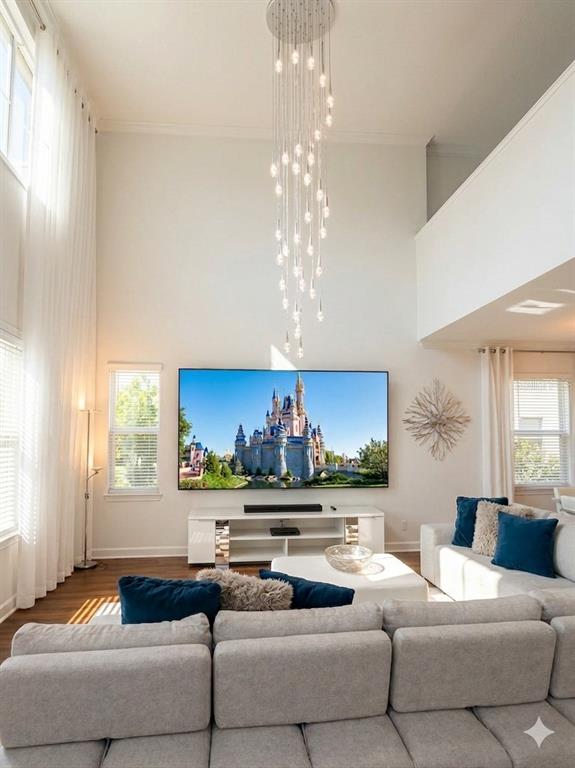 A living room features a tall ceiling, a cascading chandelier, and a large wall-mounted television — 2997 BUCCANEER PALM ROAD, KISSIMMEE, FL