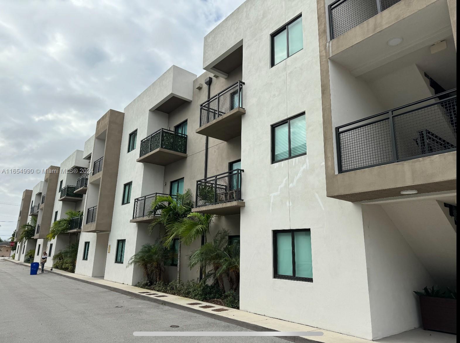 A multi-story apartment building exterior features white stucco walls, dark metal railings, and small balconies — 640 W 18th St # 107, Hialeah FL 33010, HIALEAH, FL