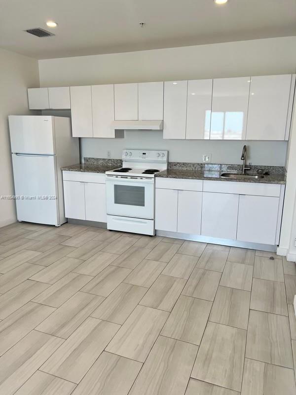A kitchen features white cabinetry, a white refrigerator, a white stove, and granite countertops — 640 W 18th St # 107, Hialeah FL 33010, HIALEAH, FL