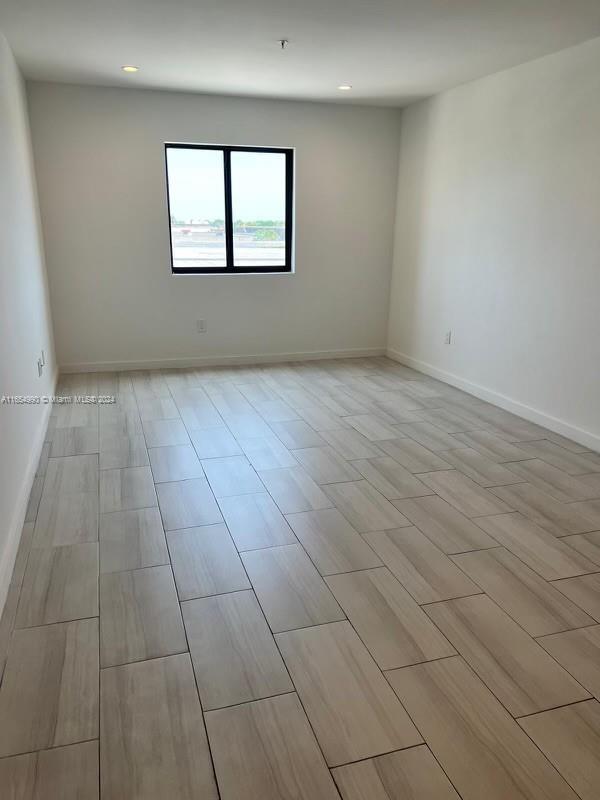 An empty room features light wood-look tile flooring, white walls, and a single window — 640 W 18th St # 107, Hialeah FL 33010, HIALEAH, FL