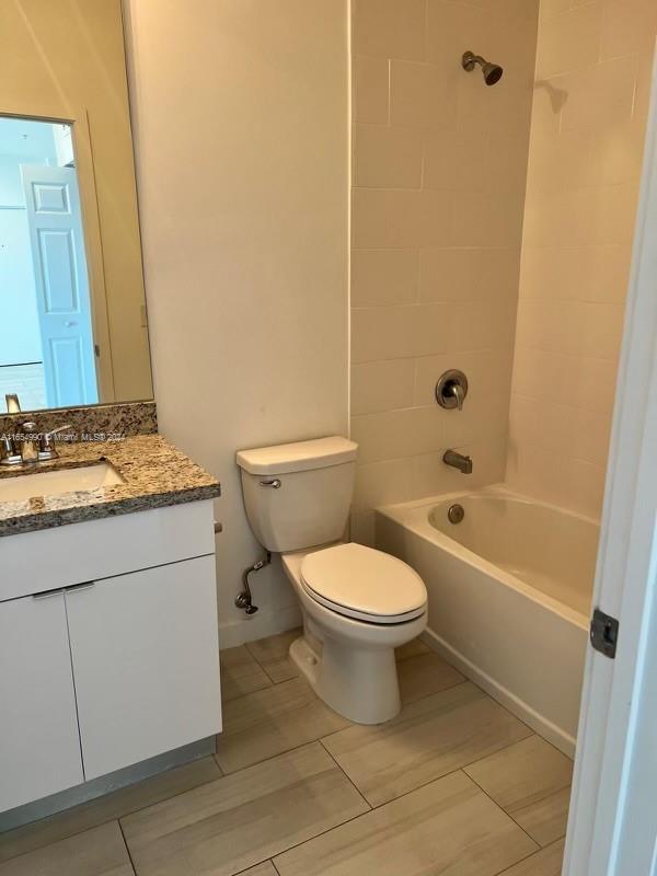 A bathroom features a granite vanity, a white toilet, and a tiled shower-tub combination — 640 W 18th St # 107, Hialeah FL 33010, HIALEAH, FL