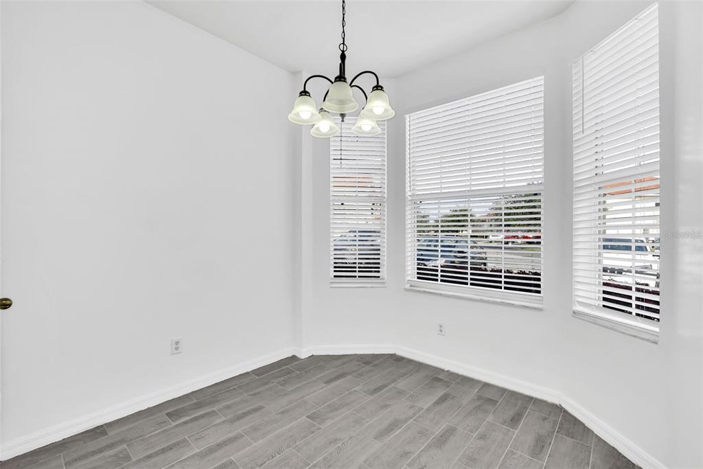 A bright dining area features white walls, gray tile flooring, and a bay window — 1160 S BEACH CIRCLE, KISSIMMEE, FL