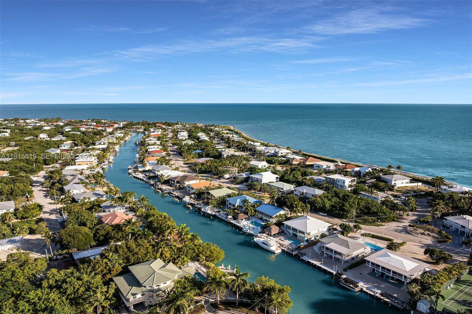 An aerial view shows houses along a canal leading to the open ocean — 232 W Seaview Dr, Duck FL 33050, DUCK, FL