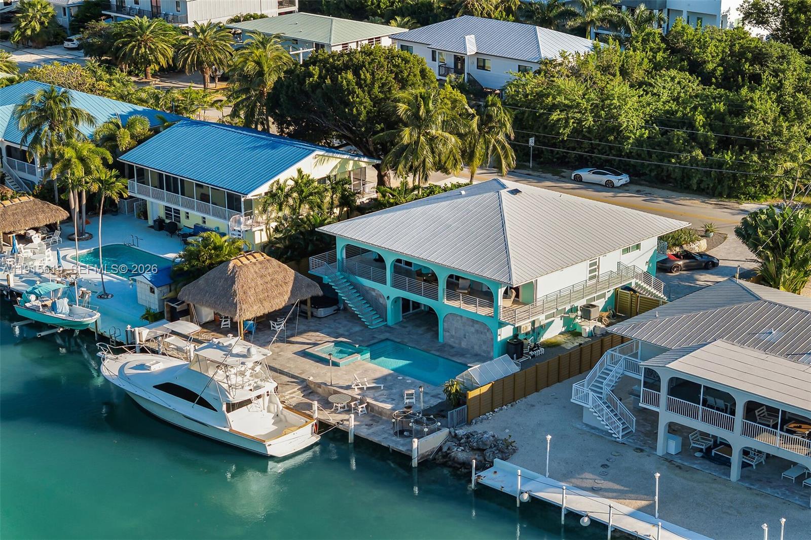 An aerial view shows a waterfront house with a pool, boat dock, and metal roof — 232 W Seaview Dr, Duck FL 33050, DUCK, FL