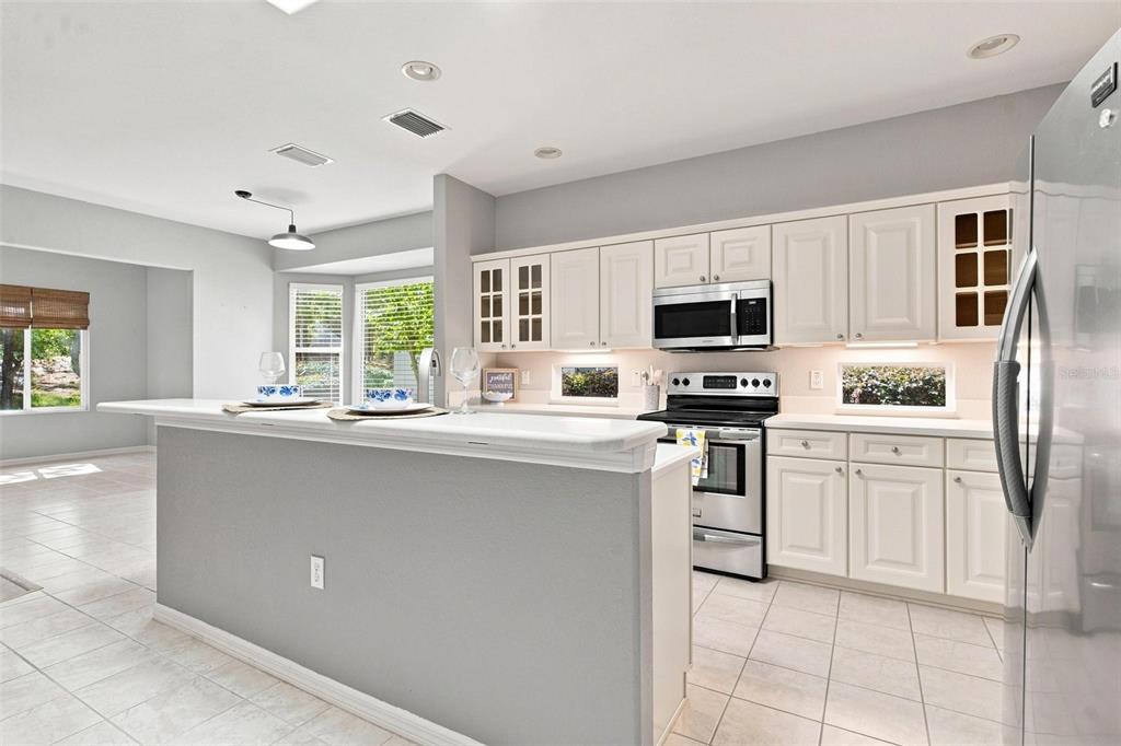A kitchen with white cabinets, stainless steel appliances, and a gray breakfast bar island — 13171 SE 97TH TERRACE ROAD, SUMMERFIELD, FL