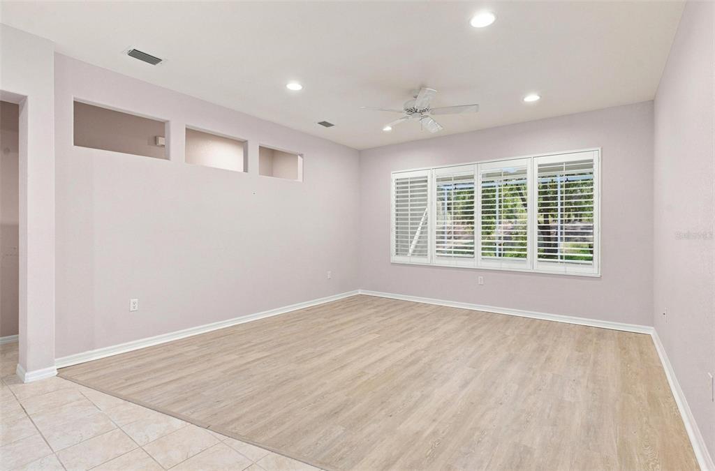 An empty room with light-colored walls, wood-look flooring, a ceiling fan, and plantation shutters — 13171 SE 97TH TERRACE ROAD, SUMMERFIELD, FL