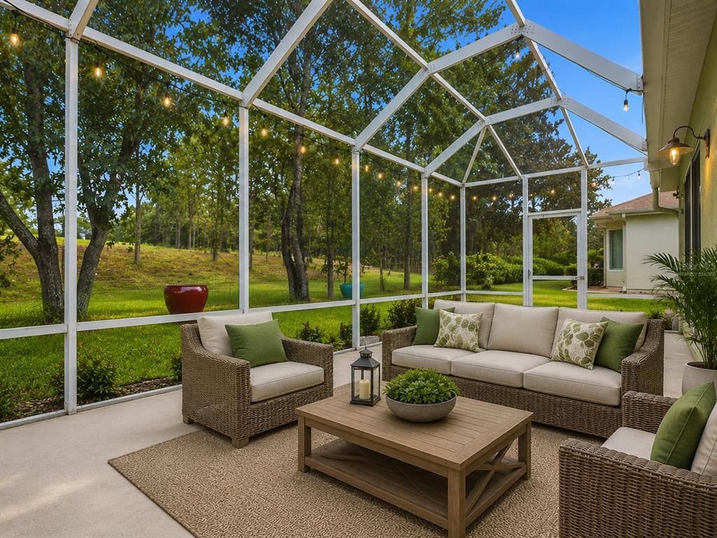 A screened-in patio features wicker furniture, a coffee table, and a view of the yard — 13171 SE 97TH TERRACE ROAD, SUMMERFIELD, FL