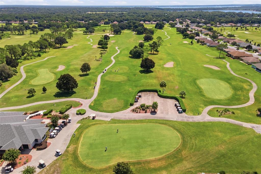 An aerial view shows a golf course with a putting green, clubhouse, and parking lot — 13171 SE 97TH TERRACE ROAD, SUMMERFIELD, FL