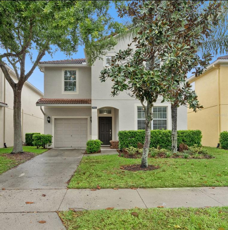 A two-story house with a beige stucco exterior, a single-car garage, and a front lawn — 8965 CUBAN PALM ROAD, KISSIMMEE, FL