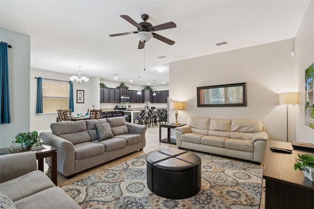 A living room with two sofas, a round ottoman, and an open kitchen in back — 8965 CUBAN PALM ROAD, KISSIMMEE, FL