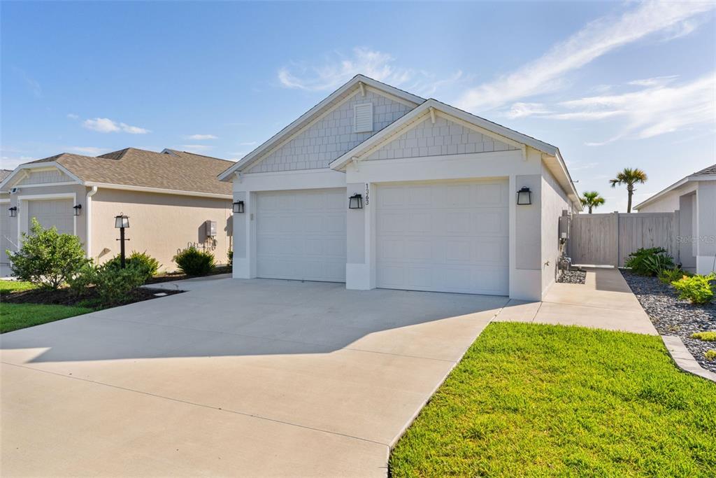 A suburban house exterior features a two-car garage, light-colored siding, and a concrete driveway — 1363 DARREN DRIVE, THE VILLAGES, FL