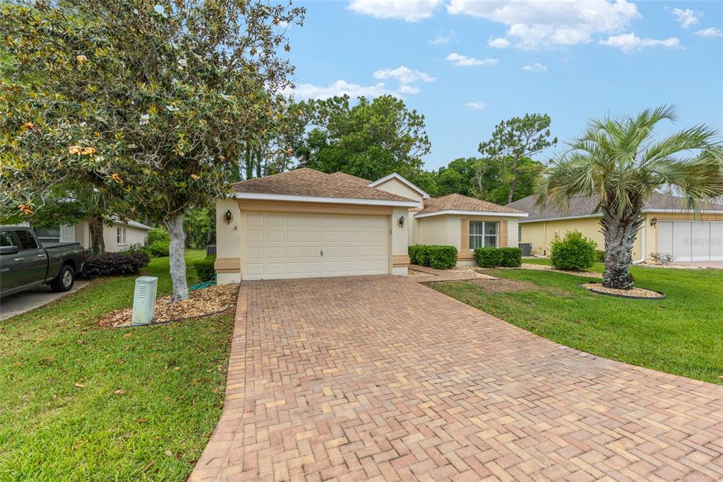 A single-story house with a beige exterior, a paved driveway, and a two-car garage — 11416 SW 69TH CIR, OCALA, FL