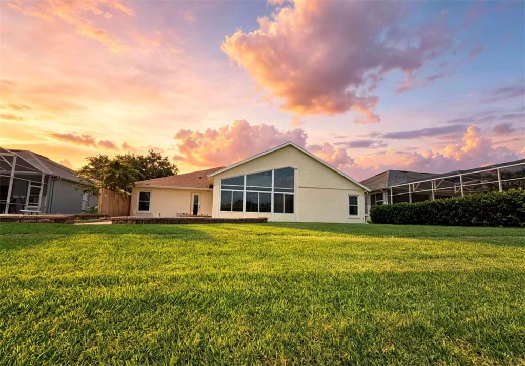 A backyard view of a house with a large screened-in porch at sunset — 731 FORESTGREEN COURT, ORLANDO, FL