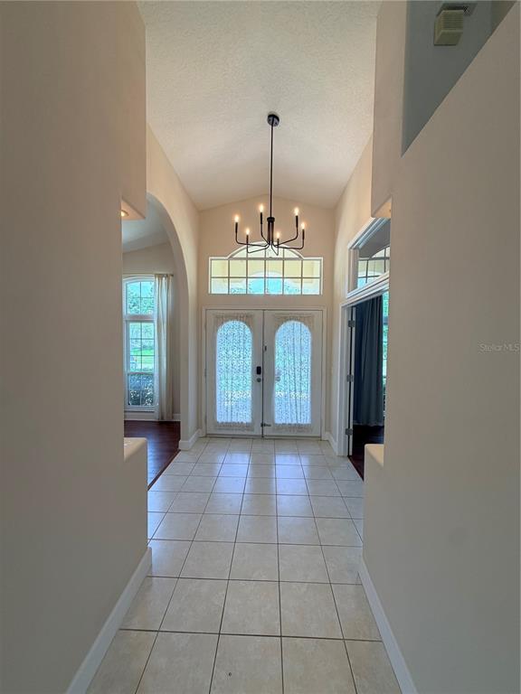 A tiled entryway features a vaulted ceiling, a modern chandelier, and double front doors — 731 FORESTGREEN COURT, ORLANDO, FL