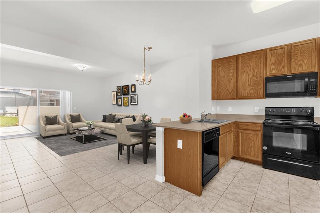 An open-concept kitchen and living area with tile flooring, wood cabinets, and sliding glass doors — 4569 CORSA LANE, KISSIMMEE, FL