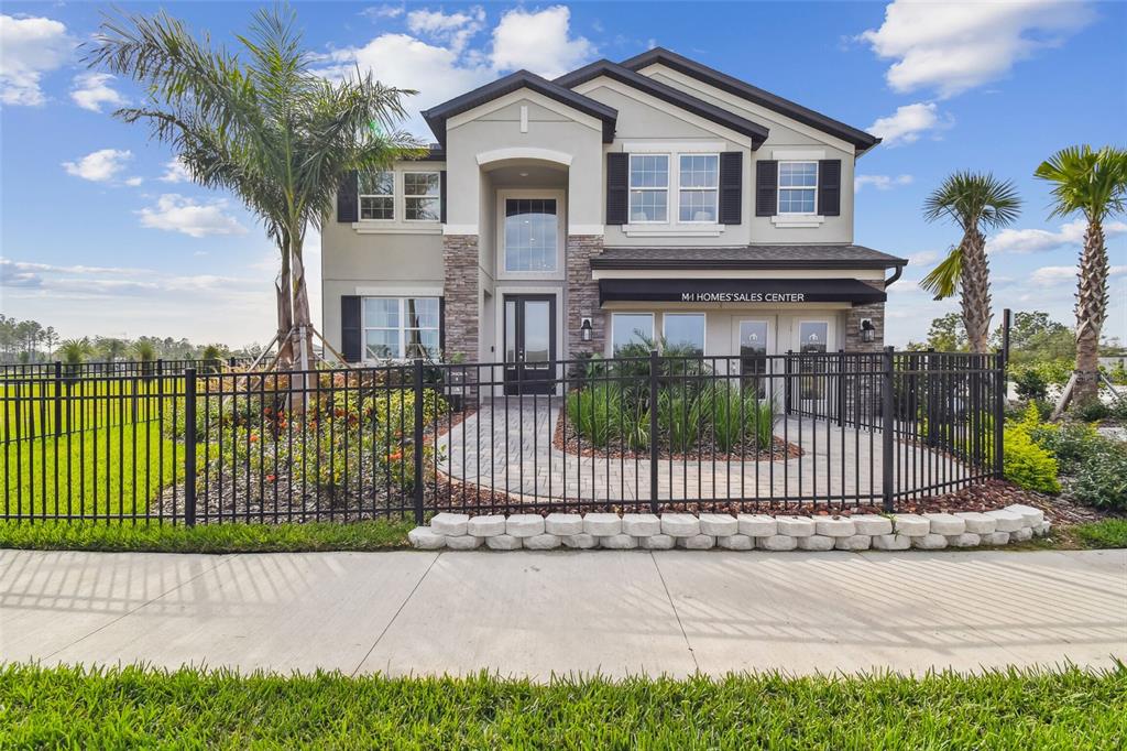 A two-story house with a stone-accented entrance and a black metal fence in front — 5950 NEWBERRY PINES AVENUE, WESLEY CHAPEL, FL