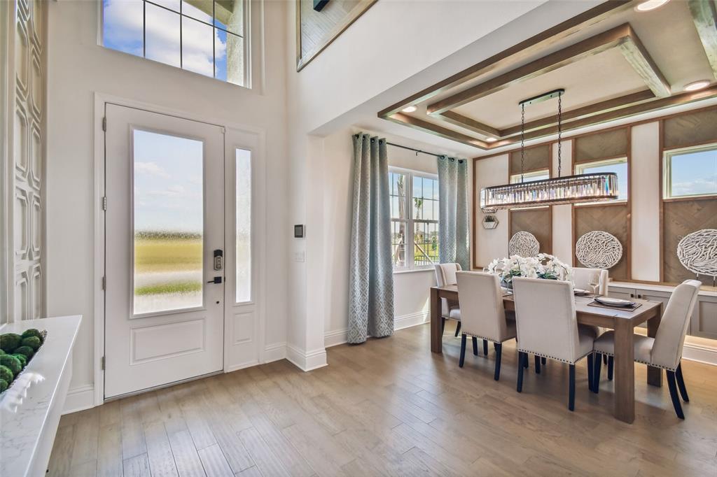A dining room with a coffered ceiling, wood floors, and an adjacent entryway — 5950 NEWBERRY PINES AVENUE, WESLEY CHAPEL, FL