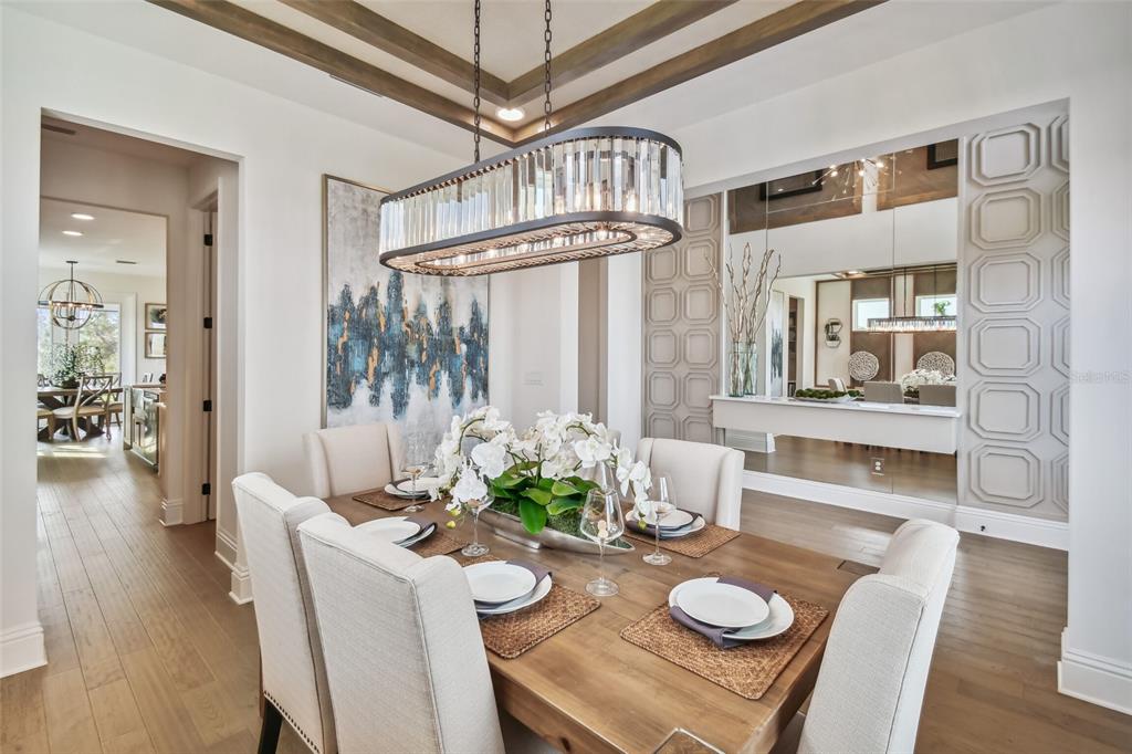 A dining room features a wooden table, upholstered chairs, a crystal chandelier, and mirrored walls — 5950 NEWBERRY PINES AVENUE, WESLEY CHAPEL, FL