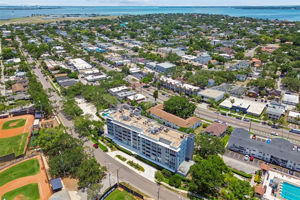 An aerial view shows a multi-story building, swimming pools, baseball fields, and a waterfront marina — 160 COLUMBIA DRIVE UNIT 206, TAMPA, FL