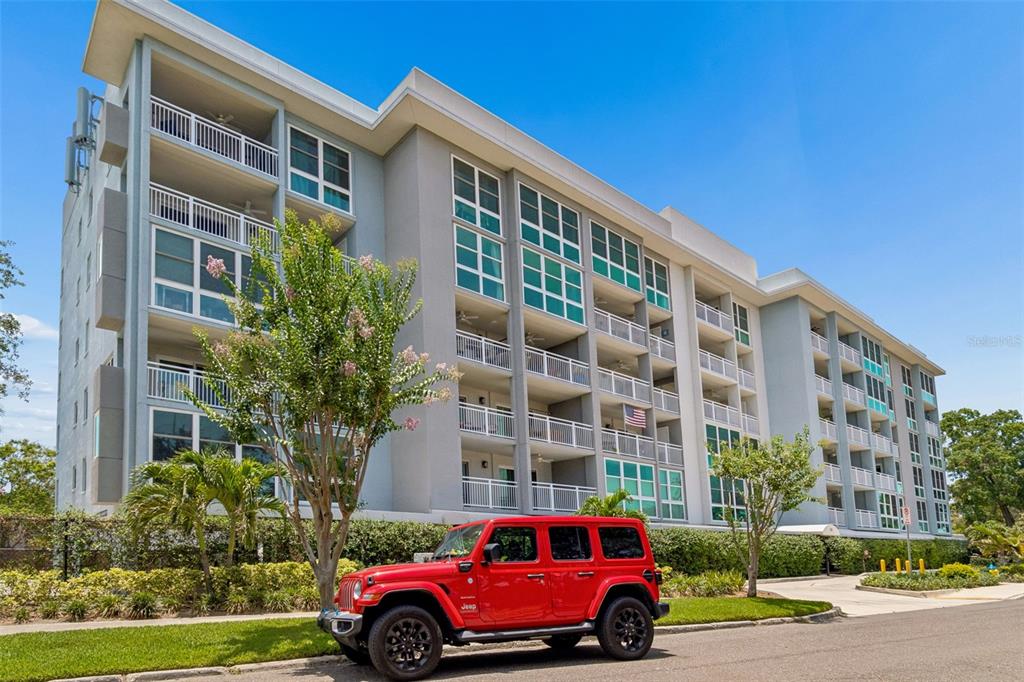 An aerial view shows a multi-story apartment building surrounded by residential streets and baseball fields — 160 COLUMBIA DRIVE UNIT 206, TAMPA, FL
