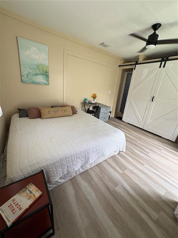 A bedroom features a bed, a small desk, and white barn doors on light flooring — 14413-B HERTHA AVENUE, ORLANDO, FL