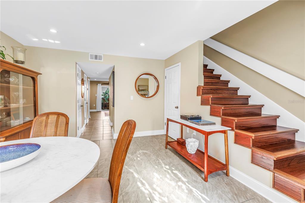 A dining area features a round table, a wooden staircase, and a hallway leading outside — 3595 41ST LANE S UNIT D, ST PETERSBURG, FL