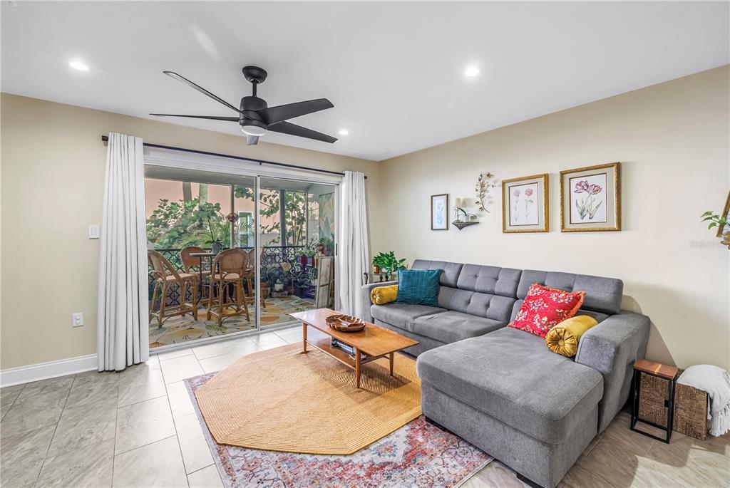 A living room features a gray sectional sofa, a coffee table, and a sliding glass door — 3595 41ST LANE S UNIT D, ST PETERSBURG, FL