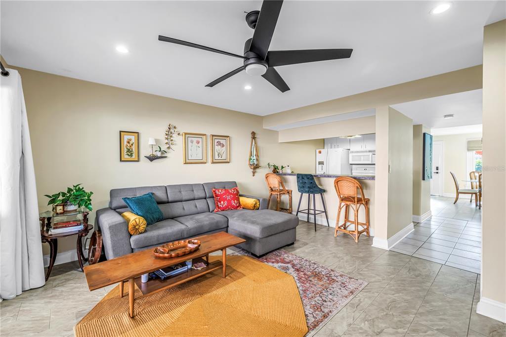 A living room features a gray sectional sofa, a wooden coffee table, and a breakfast bar — 3595 41ST LANE S UNIT D, ST PETERSBURG, FL
