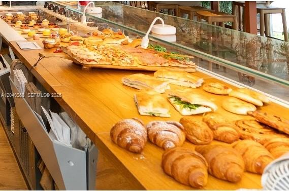 A bakery counter displays various pastries, sandwiches, and pizzas on a wooden surface — 488 NE 18 St, Miami FL 33132, MIAMI, FL