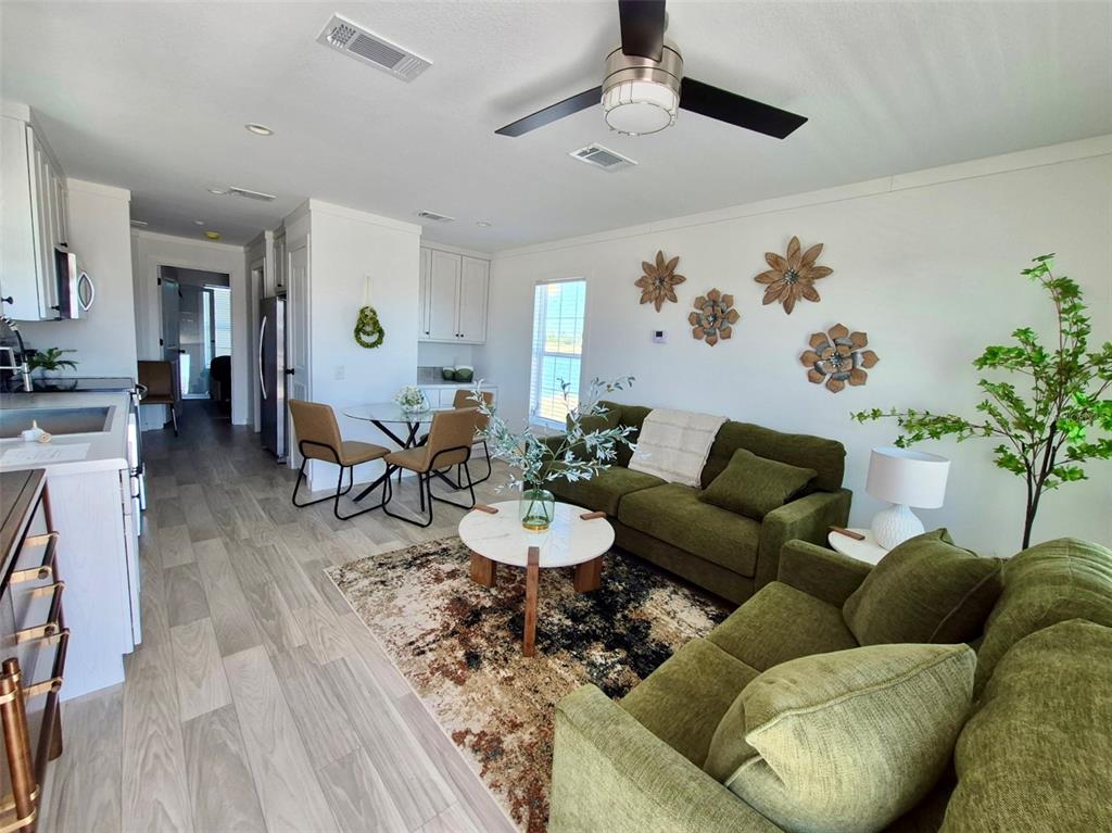 A living room and dining area feature olive green sofas, a patterned rug, and white cabinetry — 0 HIGHWAY 630 E UNIT 74, LAKE WALES, FL