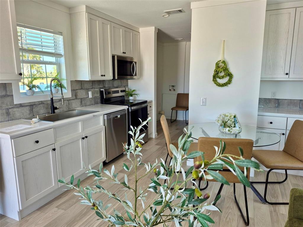 A kitchen with white cabinets, stainless steel appliances, and a small dining area — 0 HIGHWAY 630 E UNIT 74, LAKE WALES, FL