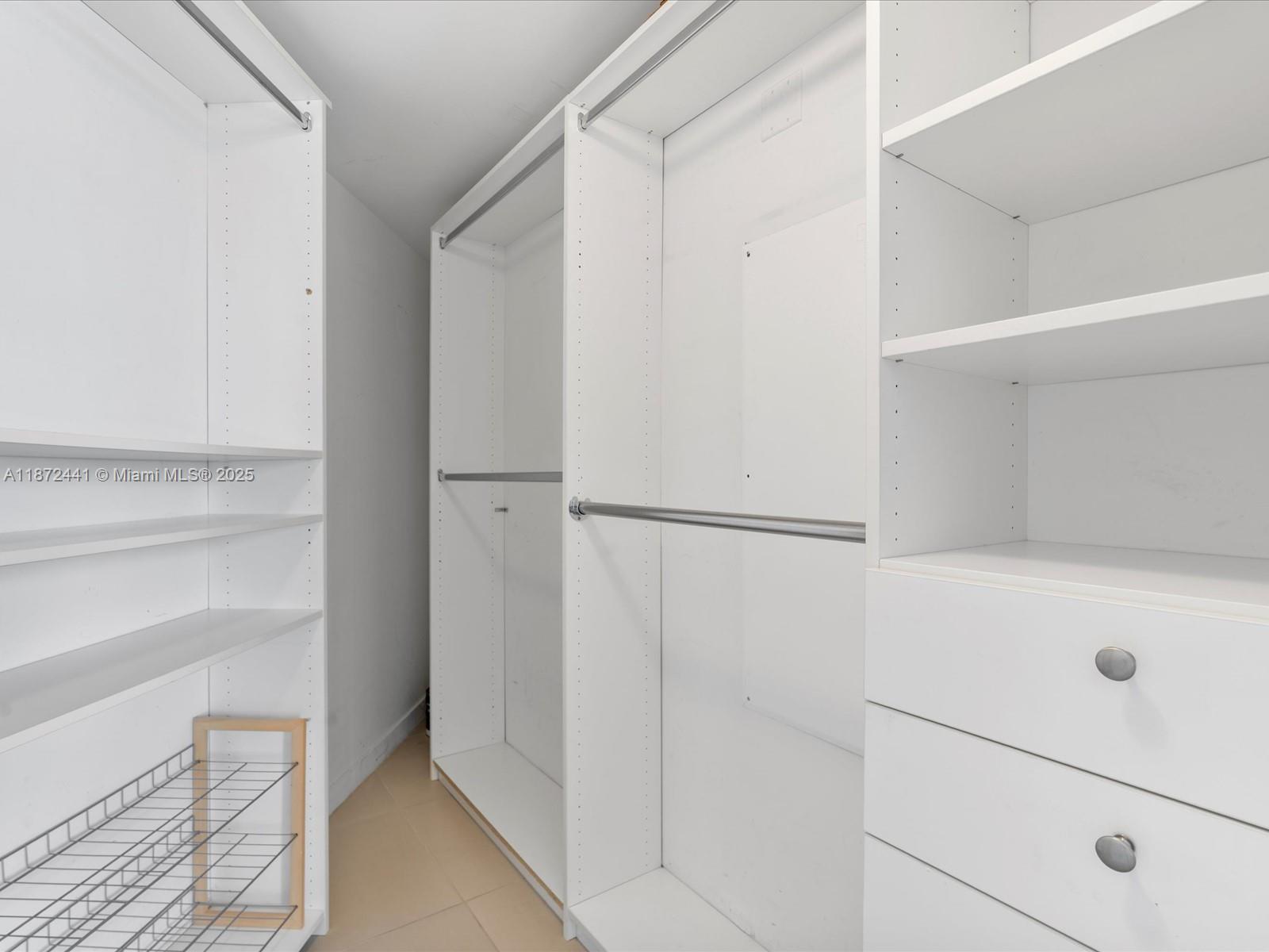 A walk-in closet features white shelving, hanging rods, and a wire shoe rack — 31 SE 6th St # 802, Miami FL 33131, MIAMI, FL