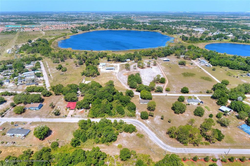An aerial view shows several houses scattered across a rural landscape near a large lake — 5514 HILLSBOROUGH STREET, WIMAUMA, FL