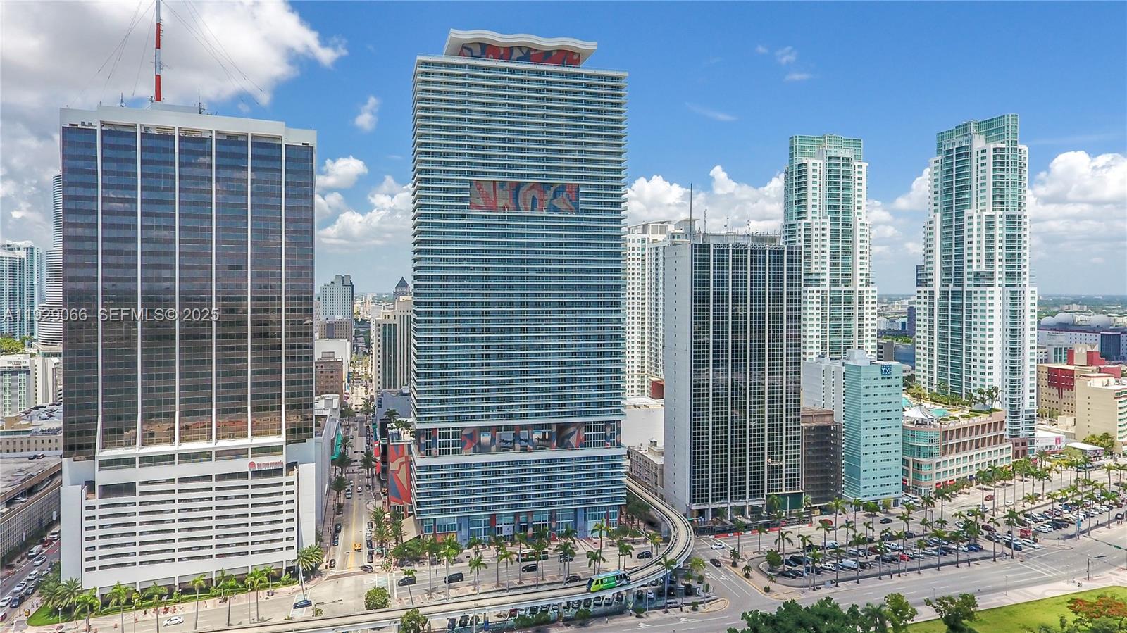 An aerial view shows several high-rise buildings in a city with a monorail track below — 50 Biscayne Blvd # 503, Miami FL 33132, MIAMI, FL