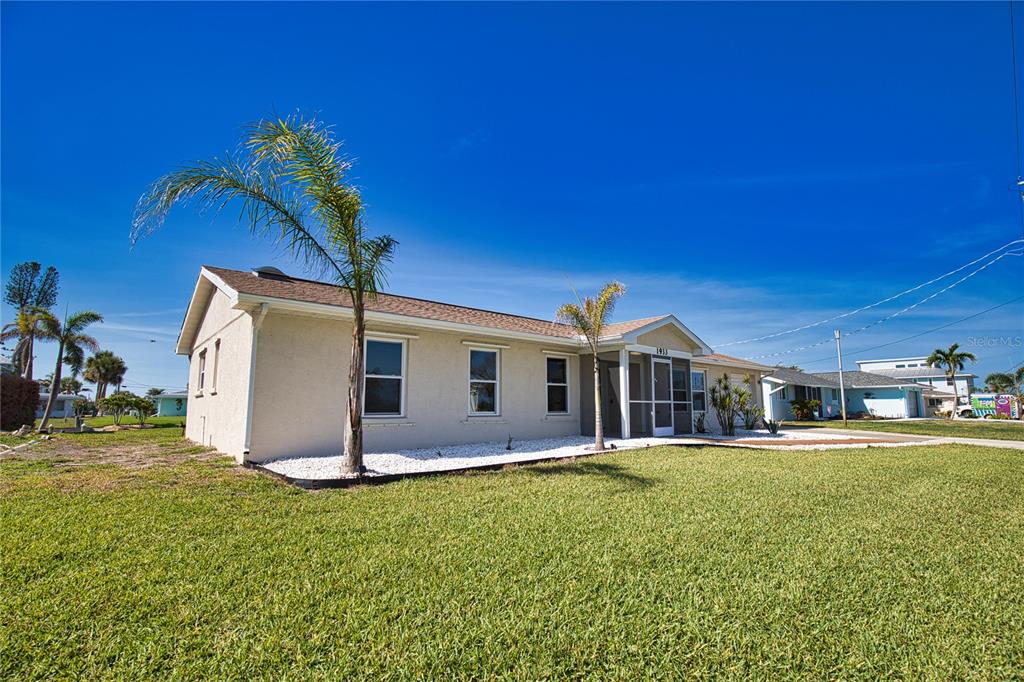 A single-story house with a screened front porch and palm trees on a sunny day — 1933 OREGON TRAIL, ENGLEWOOD, FL