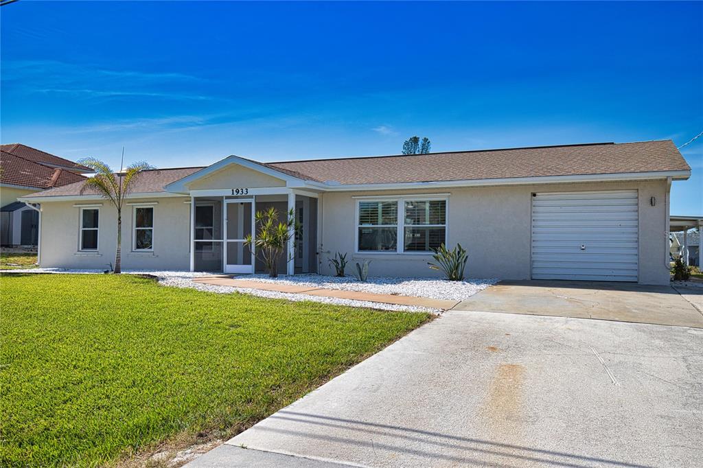 A single-story house with a white stucco exterior, a screened entryway, and a concrete driveway — 1933 OREGON TRAIL, ENGLEWOOD, FL