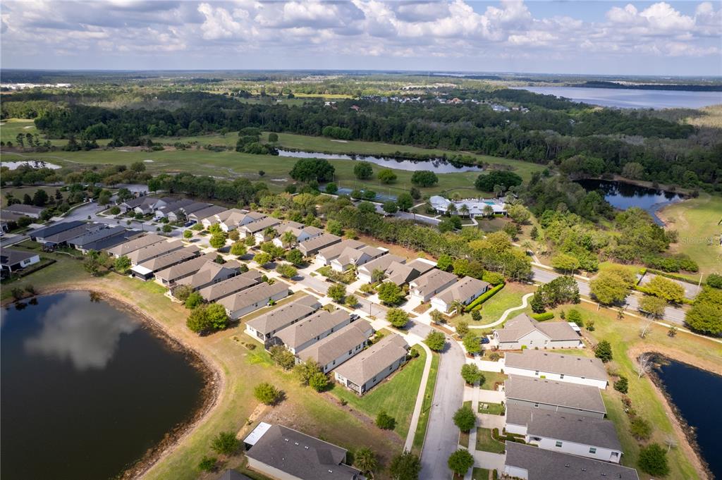 An aerial view shows a residential neighborhood with townhomes, ponds, and a golf course — 3464 SAGEBRUSH STREET, HARMONY, FL
