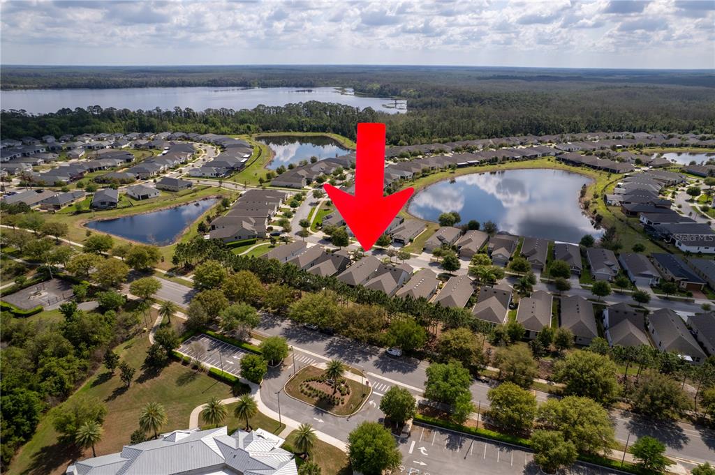 An aerial view shows a residential neighborhood with houses, a lake, and a red arrow — 3464 SAGEBRUSH STREET, HARMONY, FL