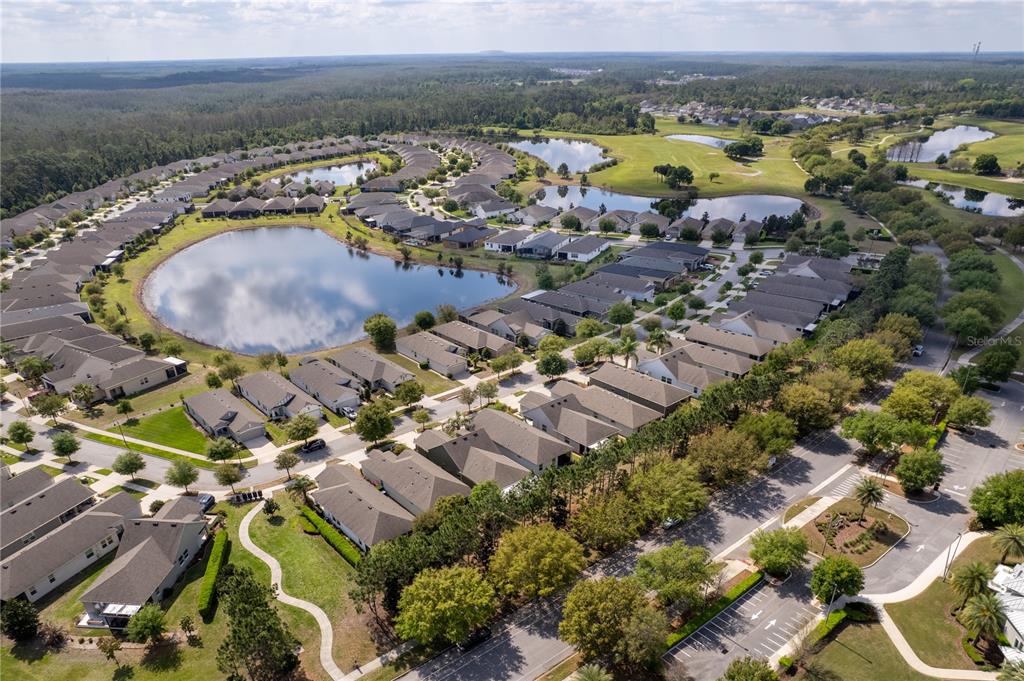Aerial view of a suburban neighborhood featuring houses surrounding a large pond and golf course — 3464 SAGEBRUSH STREET, HARMONY, FL