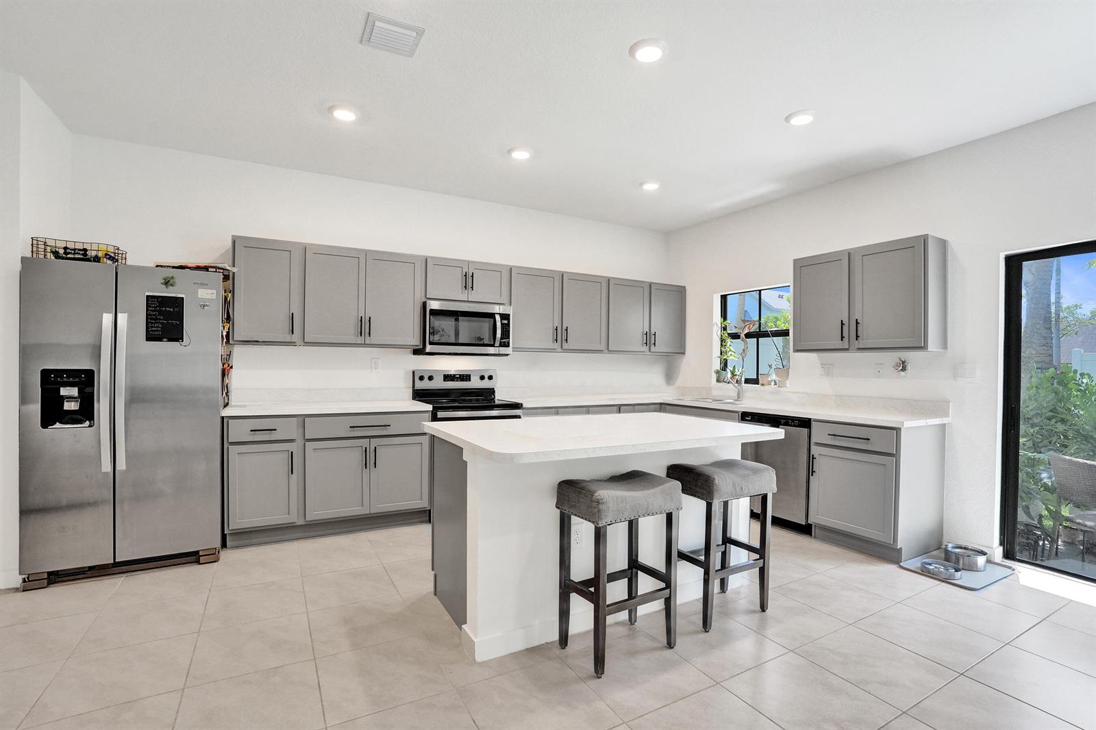 A kitchen with gray cabinets, stainless steel appliances, a white island, and light tile flooring — 975 NW 3rd Terrace, Pompano Beach FL 33060, POMPANO BEACH, FL