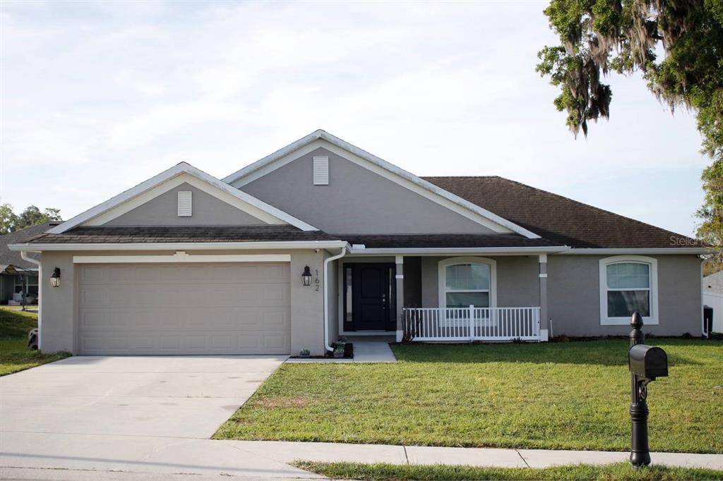 A single-story house with a gray stucco exterior, a two-car garage, and a front porch — 162 NW 44TH STREET, OCALA, FL