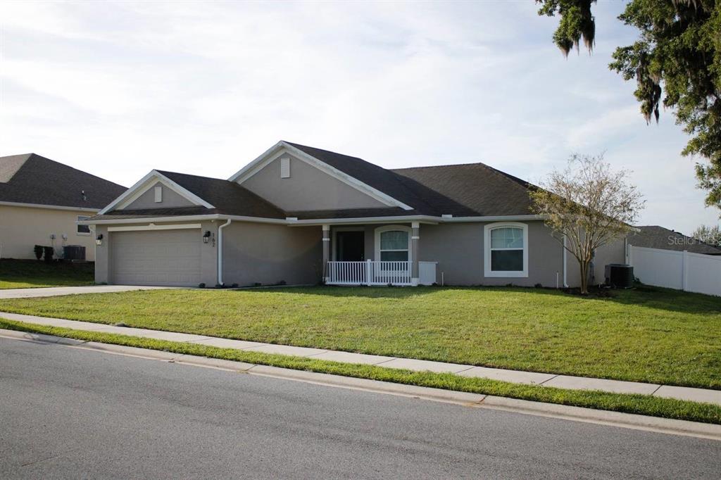 A single-story suburban house with a tan stucco exterior, a two-car garage, and a front porch — 162 NW 44TH STREET, OCALA, FL