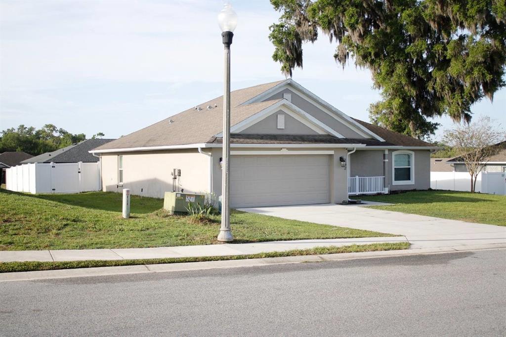 A single-story suburban house with a two-car garage, beige stucco siding, and a streetlamp — 162 NW 44TH STREET, OCALA, FL