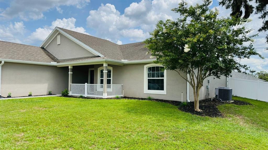 A single-story house with a beige stucco exterior, a covered porch, and a large tree — 162 NW 44TH STREET, OCALA, FL