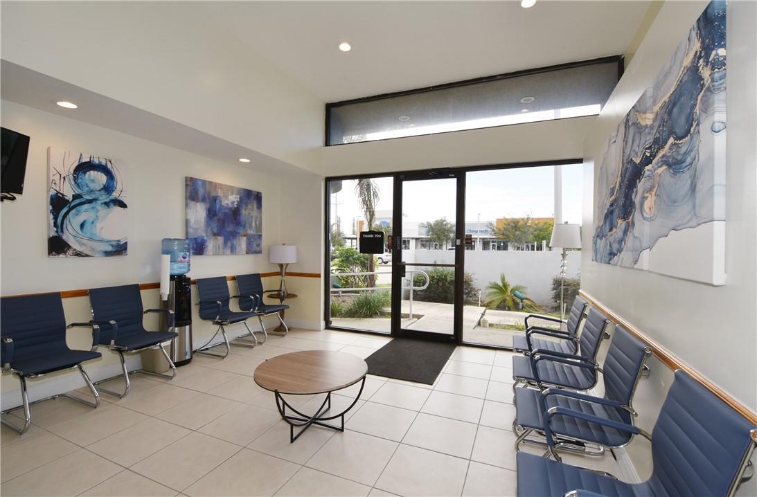 A waiting room features blue chairs, a round coffee table, and abstract wall art — 1820 E Commercial Boulevard, Fort Lauderdale FL 33308, FORT LAUDERDALE, FL