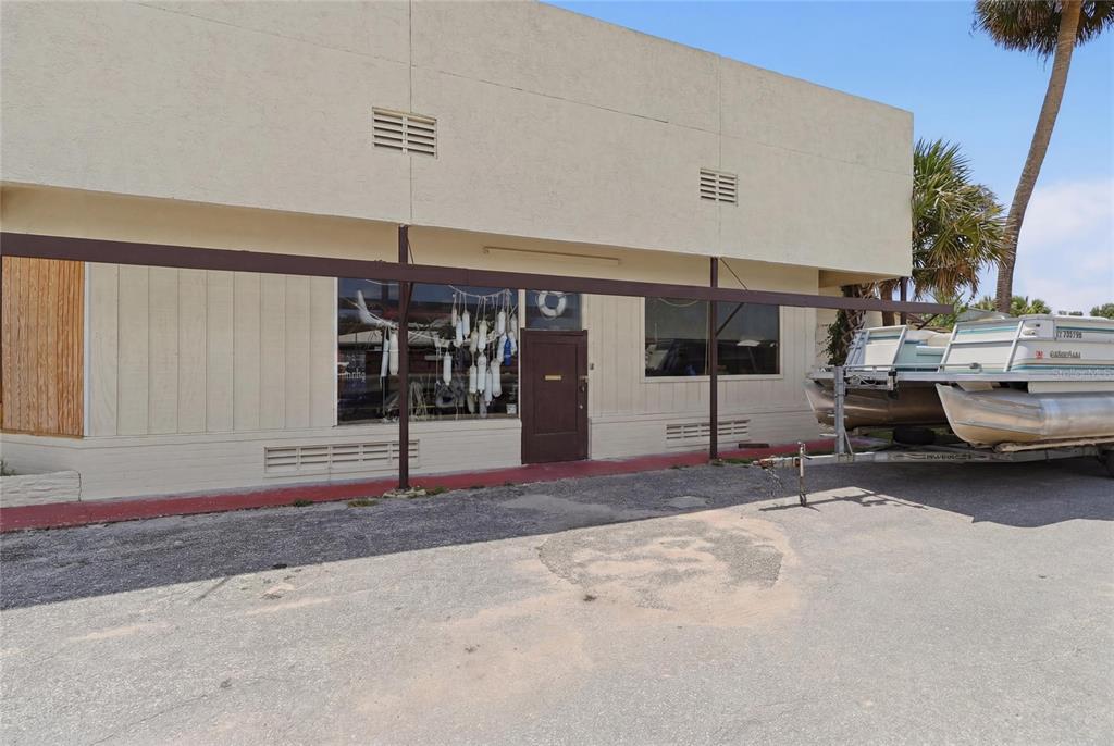 A single-story commercial building with a brown door, large windows, and a boat on a trailer — 1200 S 14TH STREET, LEESBURG, FL
